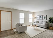 Thumbnail 28 of 28 - A living room with a grey couch, a grey armchair, a wooden coffee table, and a white door.