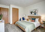 Thumbnail 23 of 25 - A bedroom with a bed, nightstand, and two doors.