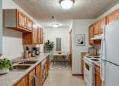 Thumbnail 30 of 31 - A kitchen with wooden cabinets and white appliances.