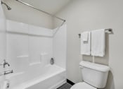 Thumbnail 51 of 51 - A white bathroom with a toilet, bathtub, and towel rack.