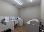 Thumbnail 17 of 29 - A row of white washing machines in a laundry room.