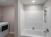 Thumbnail 13 of 16 - A white bathroom with a microwave and a bathtub.
