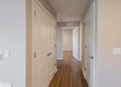 Thumbnail 63 of 78 - A long hallway with white walls and wood floors.