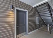 Thumbnail 2 of 16 - A dark grey door is on the left side of a staircase.