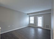 Thumbnail 6 of 31 - A room with a door, two windows, and a light switch on the wall.