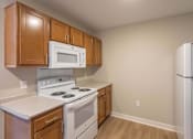Thumbnail 4 of 16 - A kitchen with a white stove and a white microwave.