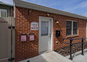 Thumbnail 29 of 29 - A brick building with a white door and a sign that says "Leasing Office".
