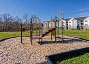 Thumbnail 62 of 76 - A playground with a slide and swings in a grassy area.