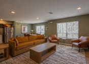 Thumbnail 19 of 32 - A living room with a brown couch, two chairs, and a coffee table.