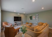 Thumbnail 28 of 32 - A living room with a brown couch, a brown chair, and a television.