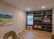 Thumbnail 35 of 37 - A room with a painting on the wall and a shelf with various items on it.