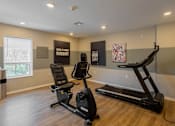 Thumbnail 18 of 32 - A room with a treadmill, a stationary bike, and a sign that says "Good Day" on the wall.