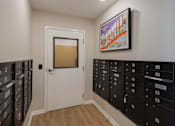 Thumbnail 22 of 32 - A hallway with a white door and a row of mailboxes on the wall.