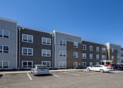 Thumbnail 25 of 32 - A parking lot with cars and apartment buildings.