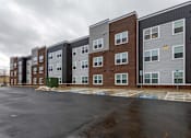 Thumbnail 28 of 37 - A row of modern apartment buildings with a parking lot in front.