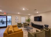 Thumbnail 33 of 37 - A living room with a yellow couch and a flat screen TV.