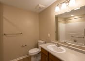Thumbnail 1 of 37 - A bathroom with a toilet, sink, mirror, and a towel bar.