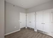 Thumbnail 13 of 29 - Three white doors are closed in a room with wood flooring.