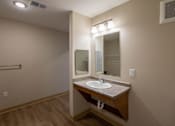 Thumbnail 11 of 24 - A bathroom with a sink, mirror, and wooden floor.