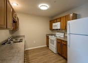 Thumbnail 18 of 24 - A kitchen with a white refrigerator, sink, and stove.