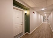 Thumbnail 19 of 24 - A long hallway with a white door and a green door.