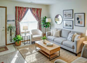 Thumbnail 15 of 15 - A living room with a grey couch, a coffee table, and a large window with red curtains.