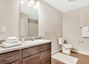 Thumbnail 50 of 51 - A bathroom with a toilet, sink, and mirror.