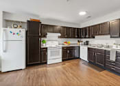 Thumbnail 32 of 33 - A kitchen with white appliances and brown cabinets.