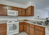 Thumbnail 30 of 31 - A kitchen with white appliances and wooden cabinets.