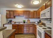 Thumbnail 26 of 28 - A kitchen with wooden cabinets and a white stove top oven.