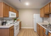 Thumbnail 15 of 16 - A kitchen with wooden cabinets and white appliances.