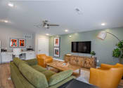 Thumbnail 22 of 30 - A living room with a green couch and a television.
