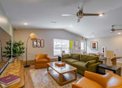 Thumbnail 27 of 30 - A living room with a green couch, a brown coffee table, and a ceiling fan.