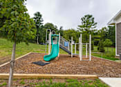 Thumbnail 18 of 30 - A playground with a green slide and a brown surface.