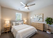 Thumbnail 49 of 52 - A bedroom with a large bed, a ceiling fan, and a window with a view of trees.