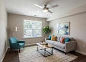 Thumbnail 50 of 52 - A living room with a blue chair, a grey couch, and a ceiling fan.