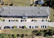Thumbnail 15 of 52 - A large building with a grey roof is surrounded by a parking lot.