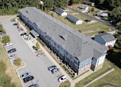 Thumbnail 16 of 52 - A large grey building with a parking lot in front.