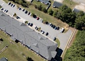 Thumbnail 22 of 52 - A large building with a grey roof is surrounded by a parking lot.