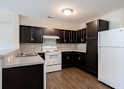 Thumbnail 40 of 52 - A kitchen with white appliances and dark brown cabinets.
