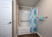 Thumbnail 43 of 52 - A white door is open to a bathroom with a white tub and a blue shower curtain.