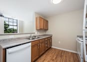 Thumbnail 29 of 58 - A kitchen with wooden cabinets and a white dishwasher.