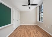 Thumbnail 30 of 58 - A room with a ceiling fan and wooden flooring.