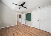Thumbnail 26 of 58 - A room with a ceiling fan and wooden floors.