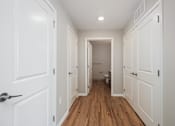 Thumbnail 45 of 58 - A hallway with white doors and a wooden floor.