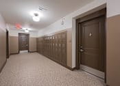 Thumbnail 44 of 58 - A long hallway with brown doors and a red exit sign.