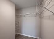 Thumbnail 21 of 58 - Empty walk-in closet with shelves and a carpeted floor.