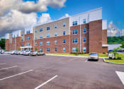 Thumbnail 5 of 64 - a large brick building with a parking lot in front of it