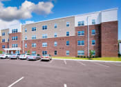 Thumbnail 7 of 64 - a large brick building with a parking lot in front of it