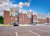 Thumbnail 8 of 64 - a large brick building with a parking lot in front of it